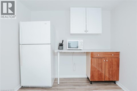 A white refrigerator is in a kitchen next to a wooden cabinet.