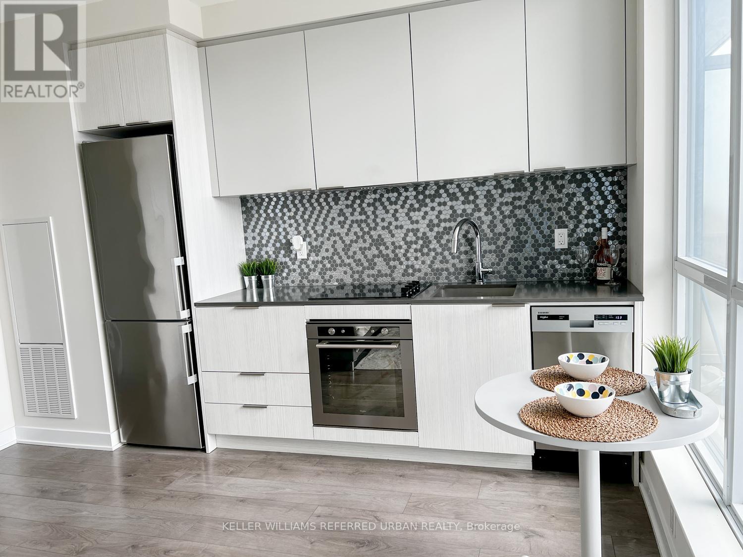 A modern kitchen with white cabinets and a black and white backsplash.