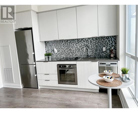 A modern kitchen with white cabinets and a black and white backsplash.