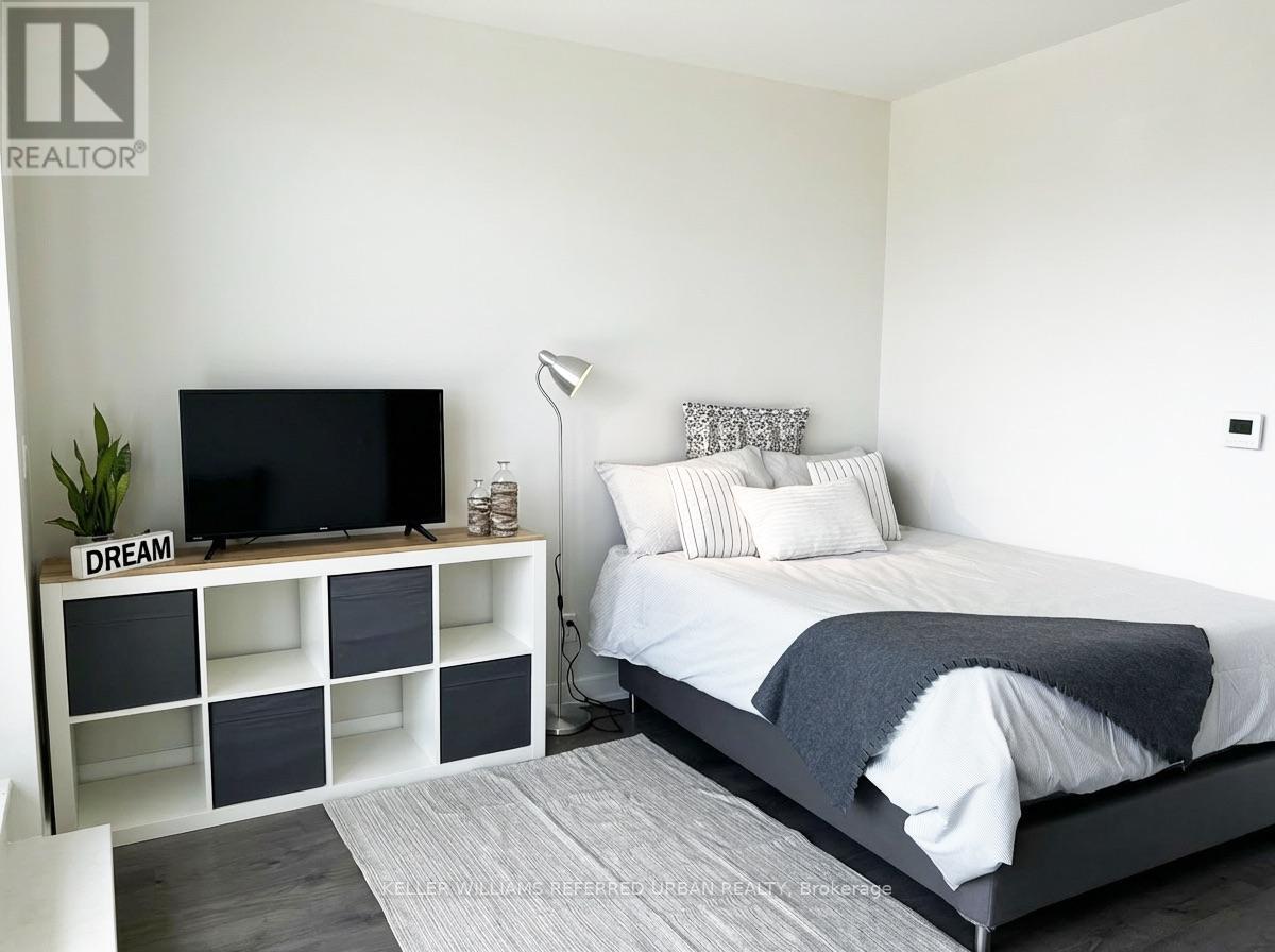 A bedroom with a bed, a television, and a plant.