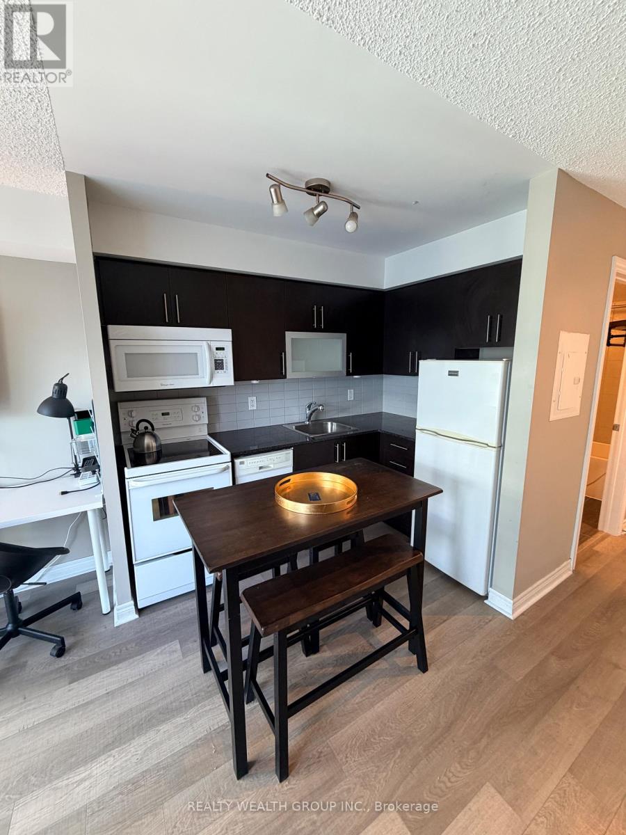 A kitchen with a table and chairs in the foreground and a refrigerator in the background.