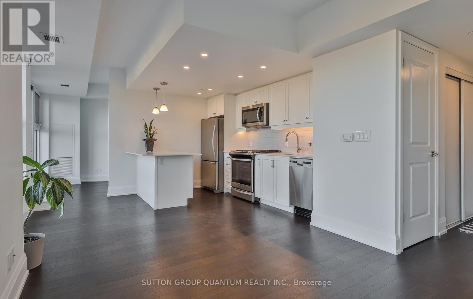 A modern kitchen with white cabinets and a wooden floor.