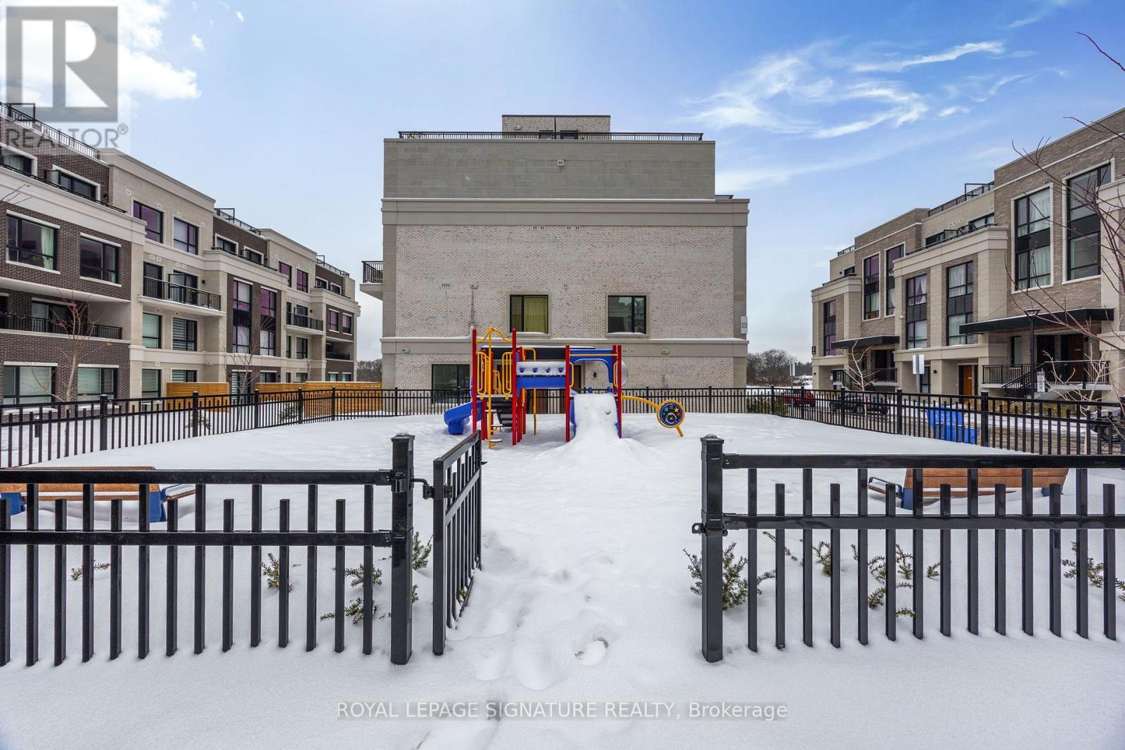 A snowy playground with a slide and a building in the background.