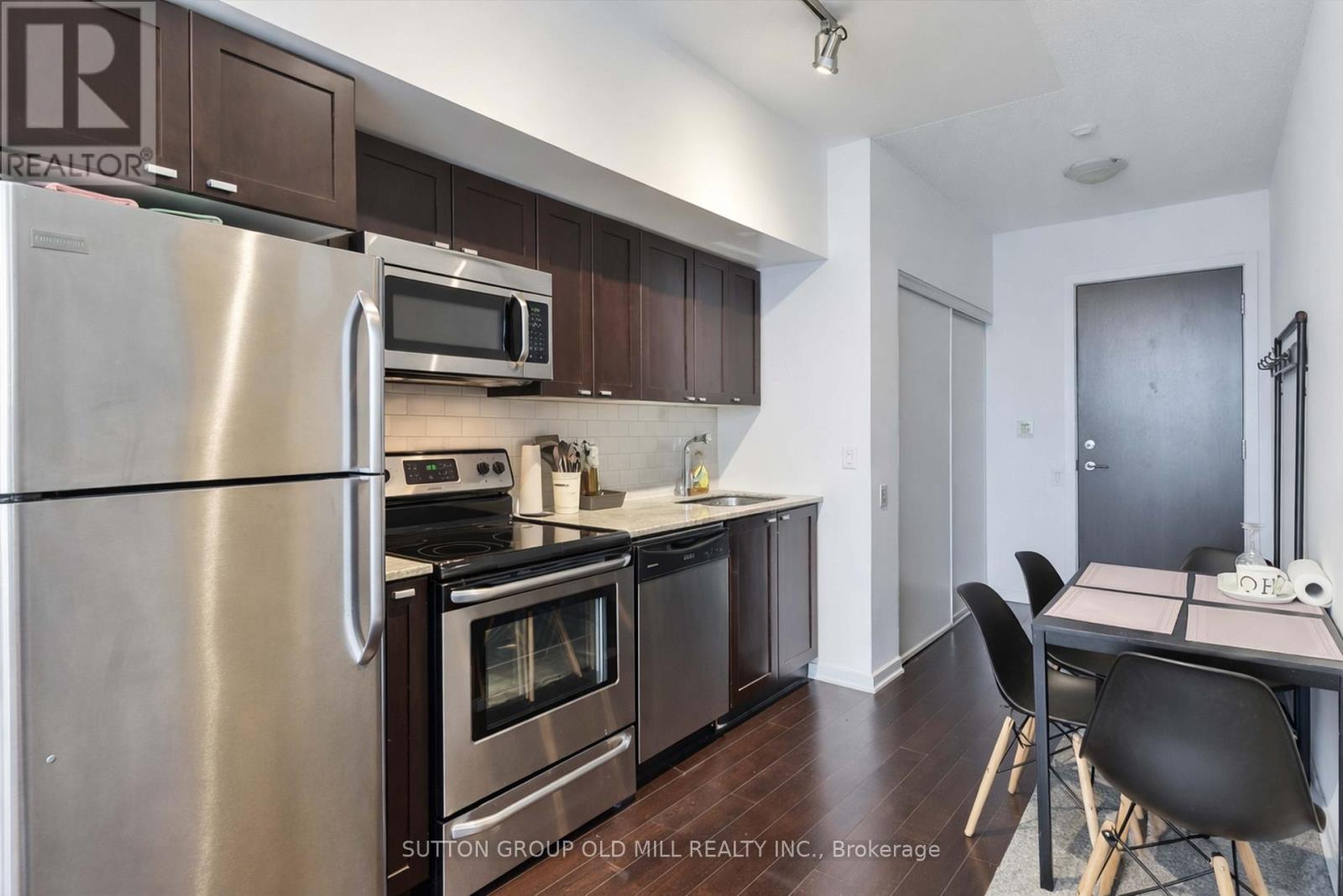 A kitchen with a stainless steel refrigerator, microwave, oven, and dining table with chairs.