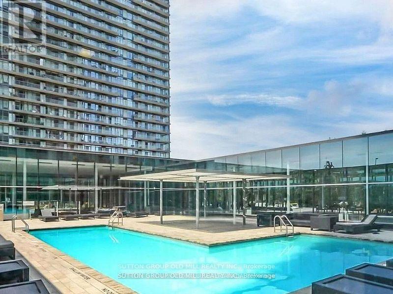 A large glass building with a pool in front.