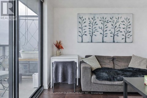 A living room with a grey couch and a painting on the wall.