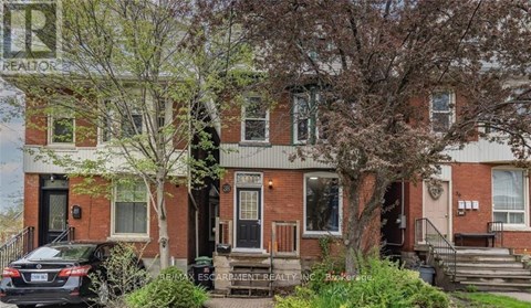 A red brick house with a black car parked in front.