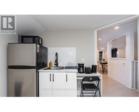 A kitchen with a refrigerator, microwave, and sink.