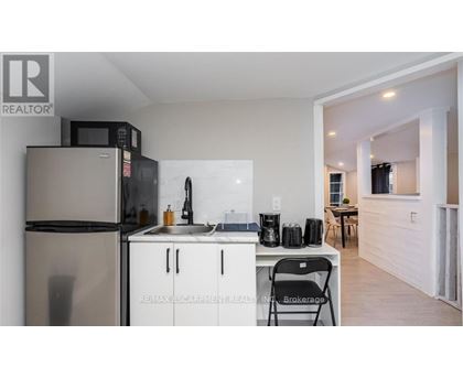 A kitchen with a refrigerator, microwave, and sink.