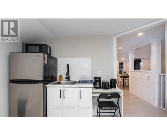 A kitchen with a refrigerator, microwave, and sink.