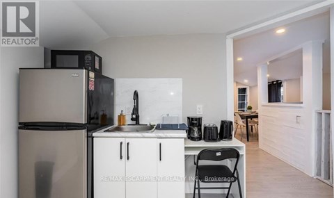 A kitchen with a refrigerator, microwave, and sink.