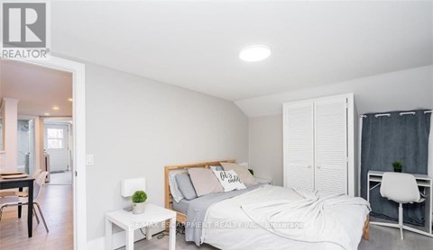 A bedroom with a bed, nightstand, and chair.
