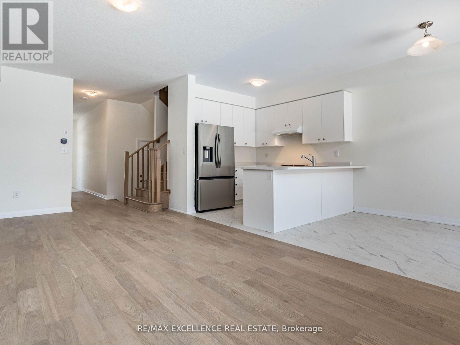A spacious kitchen with white cabinets and a wooden floor.