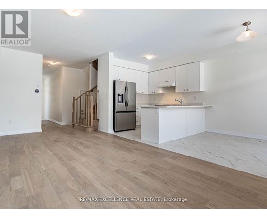 A spacious kitchen with white cabinets and a wooden floor.