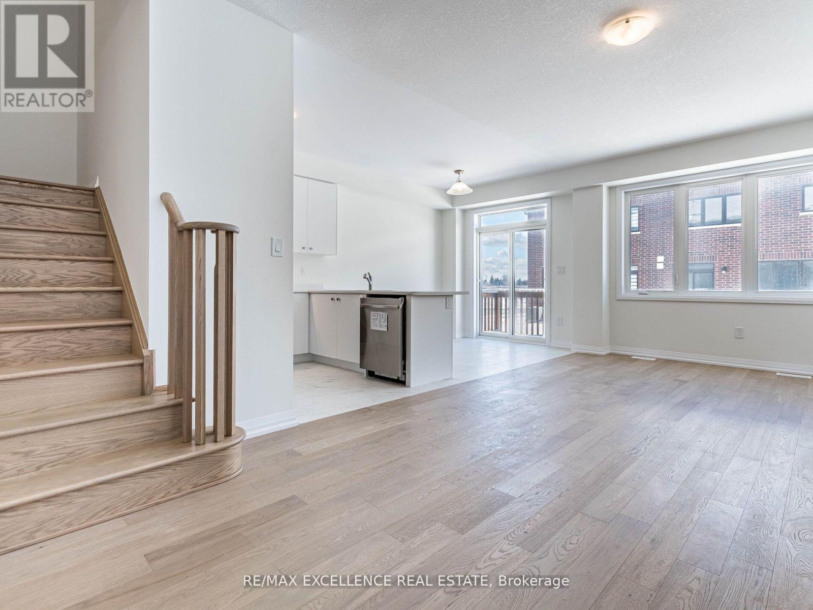 A spacious room with wooden flooring and a staircase leading to the upper level.