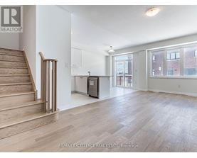 A spacious room with wooden flooring and a staircase leading to the upper level.