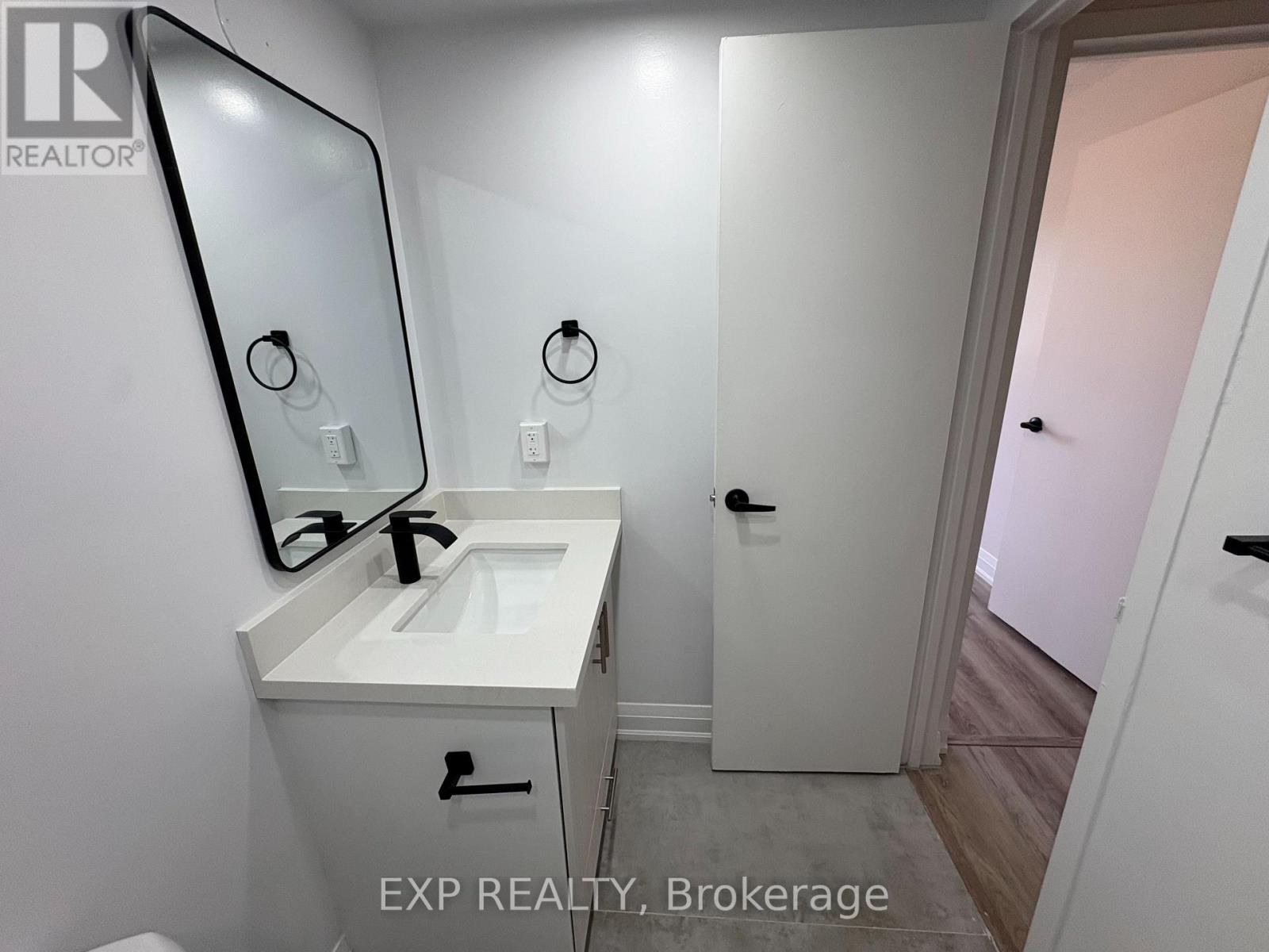 A bathroom with a sink, mirror, and a door.