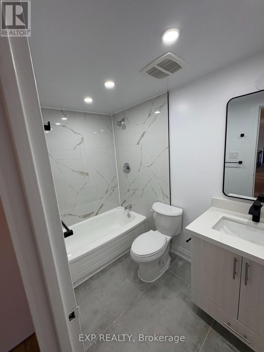 A white bathroom with marble tiles and a bathtub.