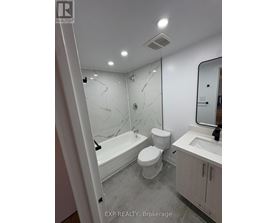 A white bathroom with marble tiles and a bathtub.