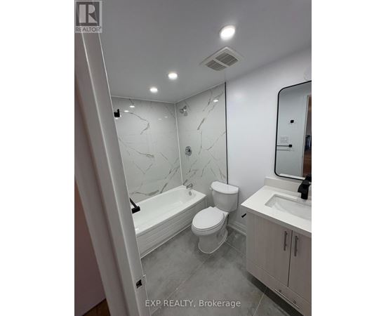 A white bathroom with marble tiles and a bathtub.