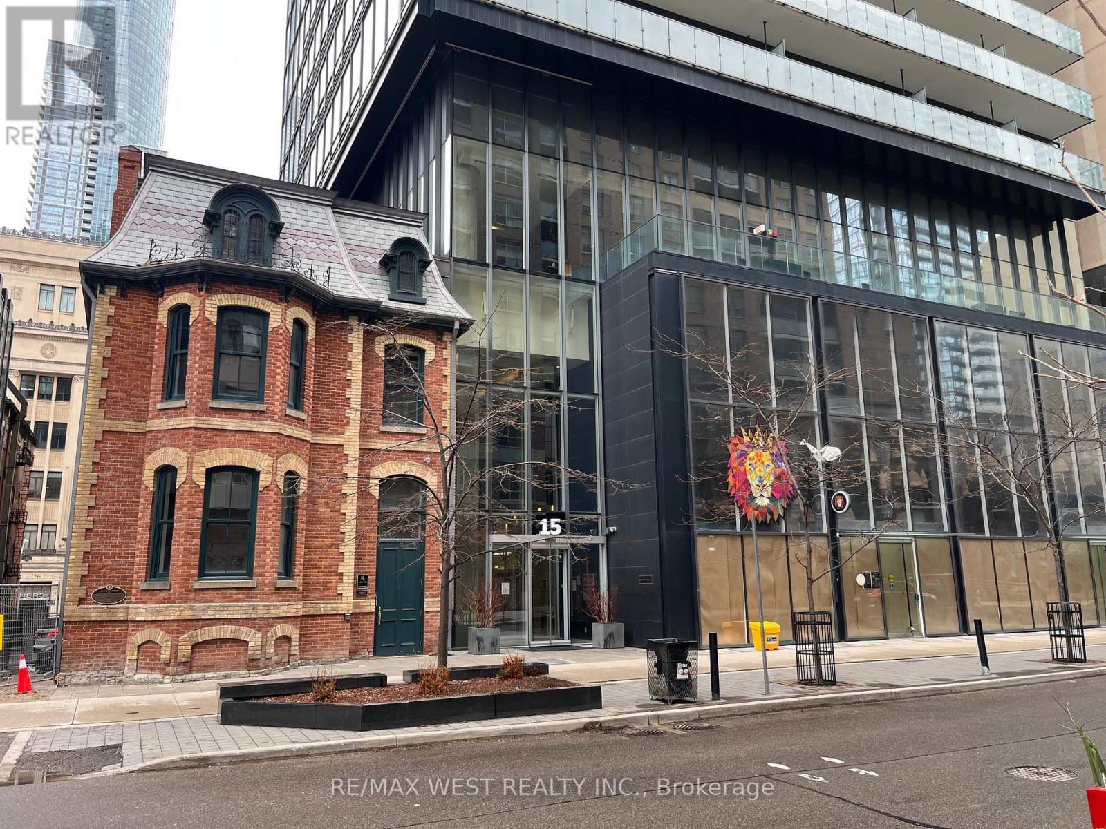 A building with a red brick facade is in front of a modern glass building.