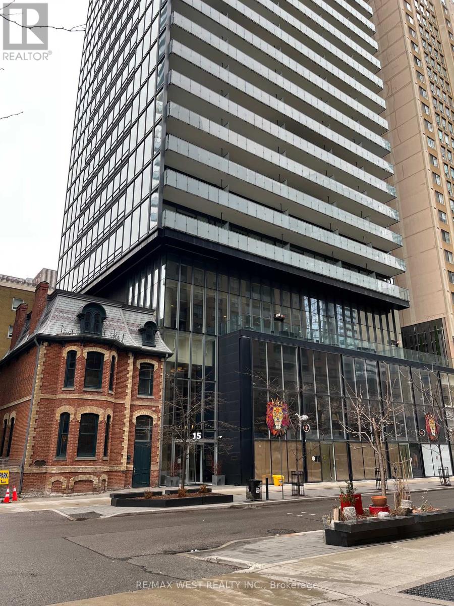 A modern building with a glass facade stands next to a smaller, older brick building.