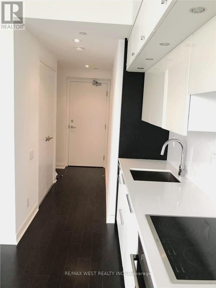 A modern kitchen with white cabinets and black countertops.