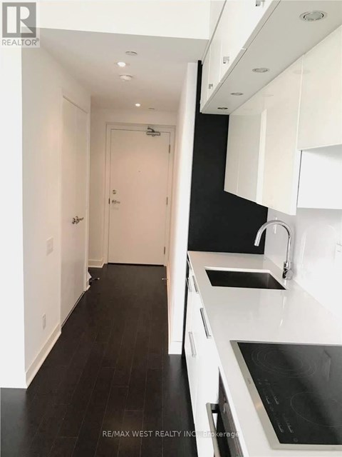 A modern kitchen with white cabinets and black countertops.