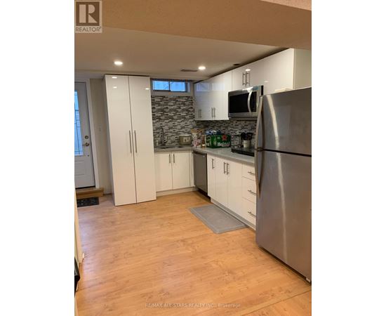 A kitchen with a refrigerator, cabinets, and a countertop.