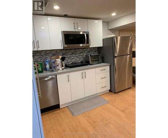 A kitchen with white cabinets and a stainless steel refrigerator.