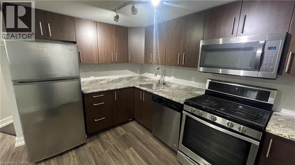 A kitchen with a refrigerator, oven, microwave, and sink.
