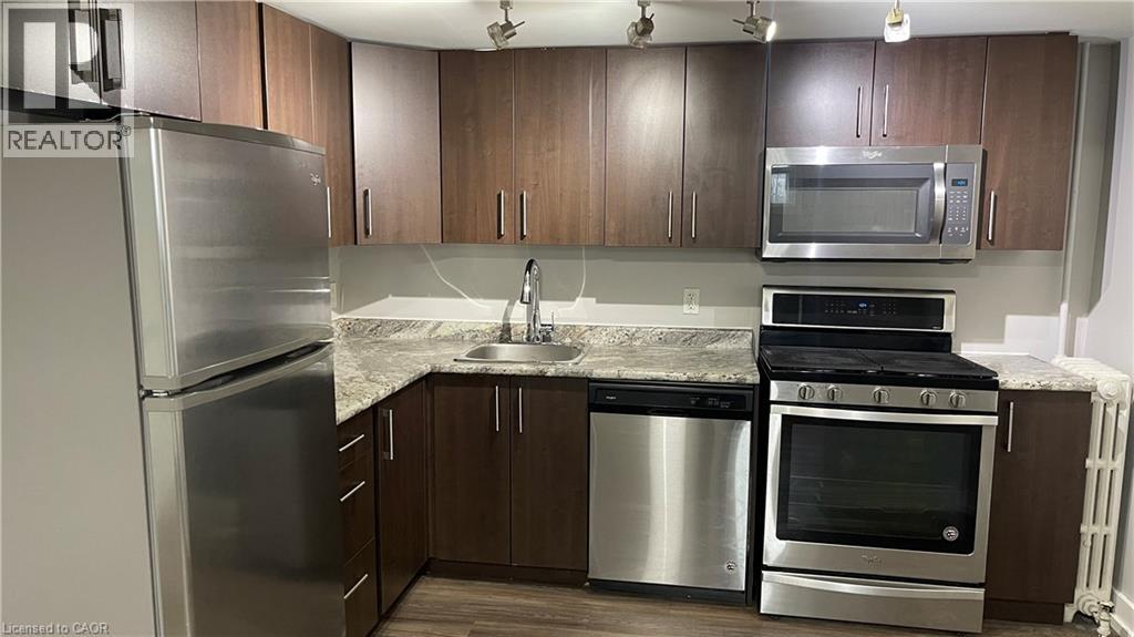 A kitchen with a refrigerator, sink, and stove.