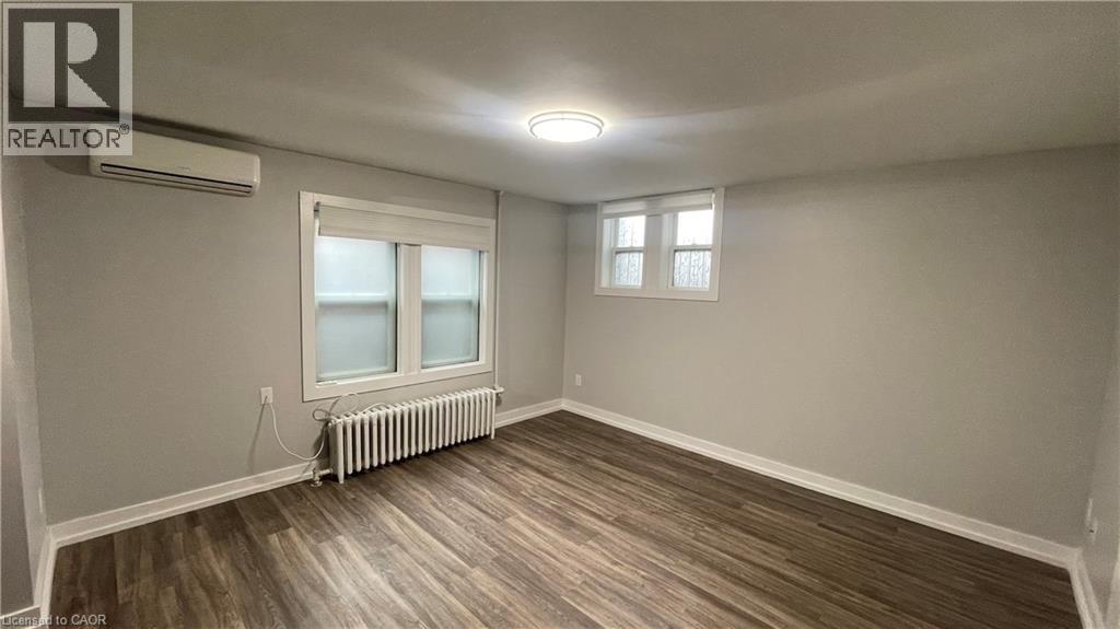 A room with wood flooring and a window with a white frame.