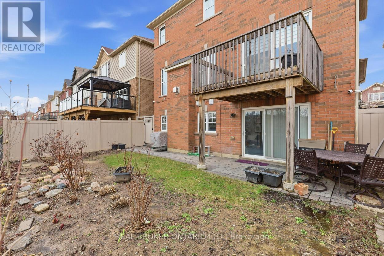 A balcony with a table and chairs is on the second floor of a brick building.