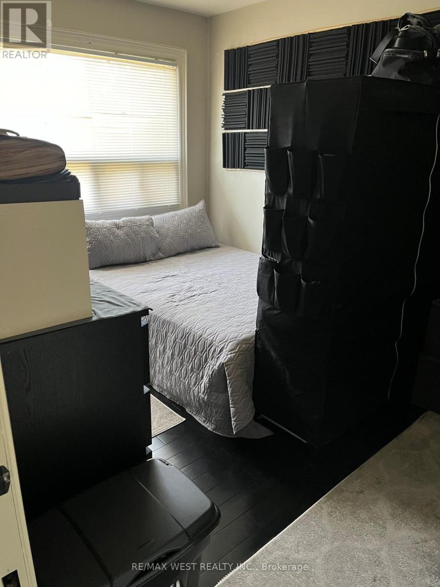 A bedroom with a bed, a black chair, and a window with blinds.