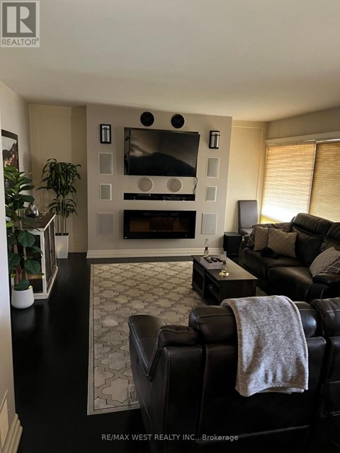 A black leather couch with a grey blanket draped over it sits in a living room.