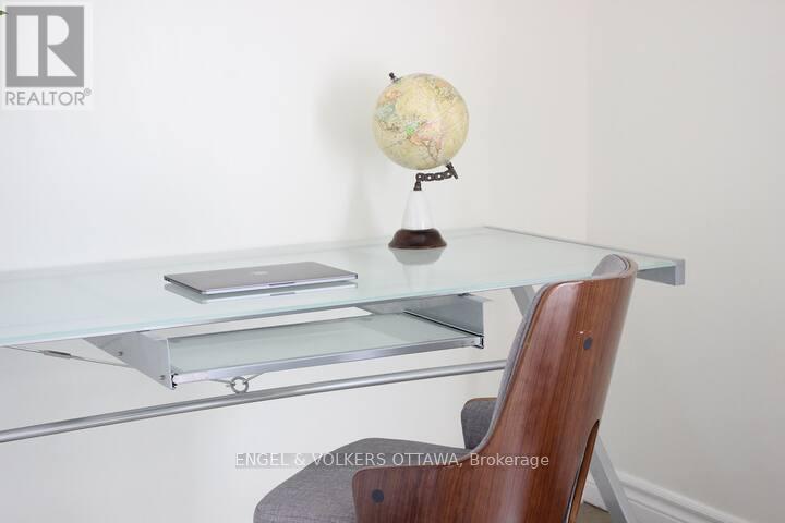 A globe on a desk with a laptop and a wooden chair.
