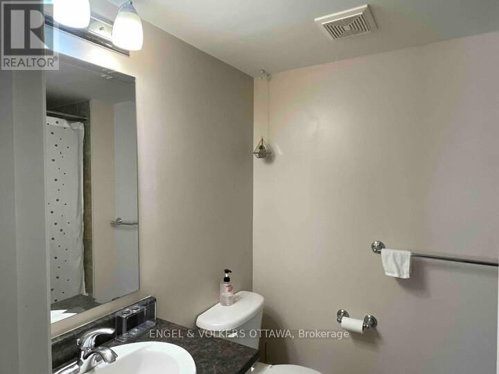 A bathroom with a toilet, sink, and mirror.