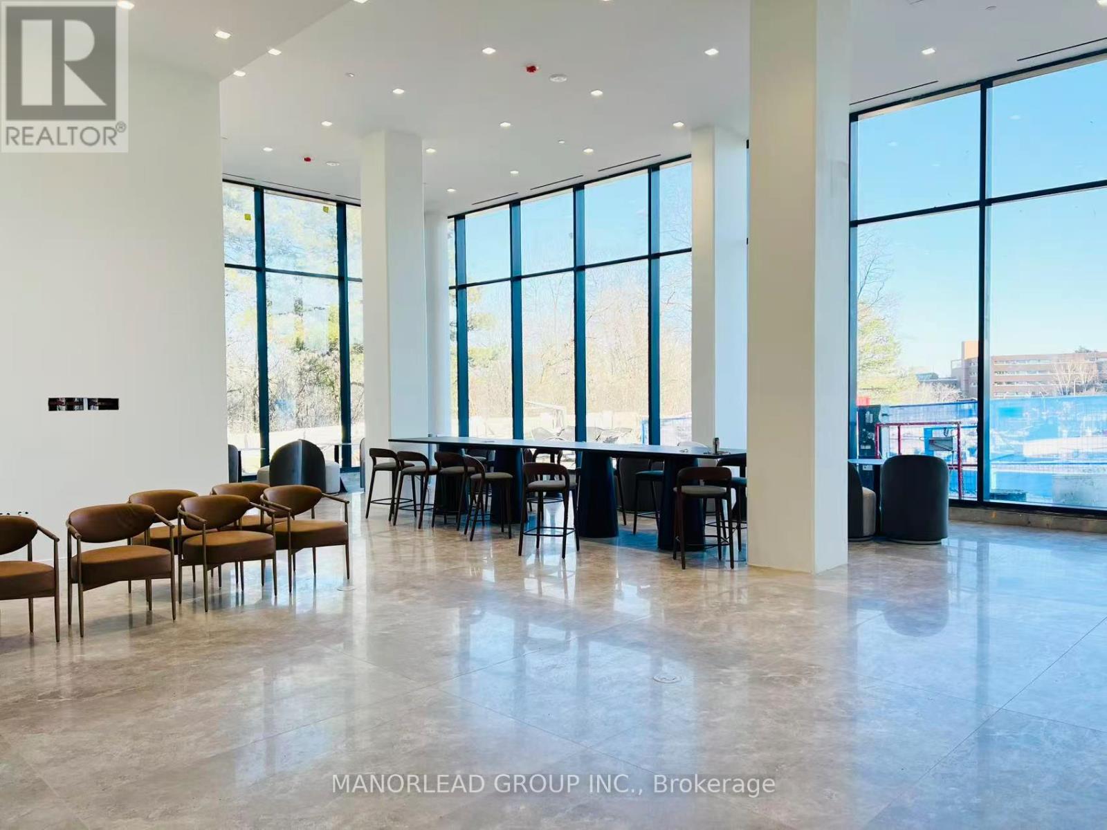 A spacious room with a long table and chairs, large windows, and a view of the outside.