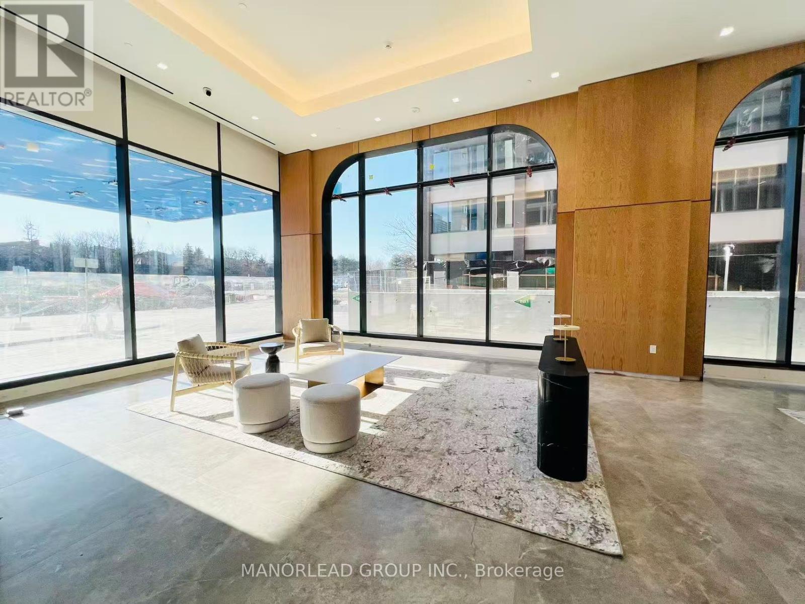 A spacious living room with a large rug and a black cylindrical object on the floor.