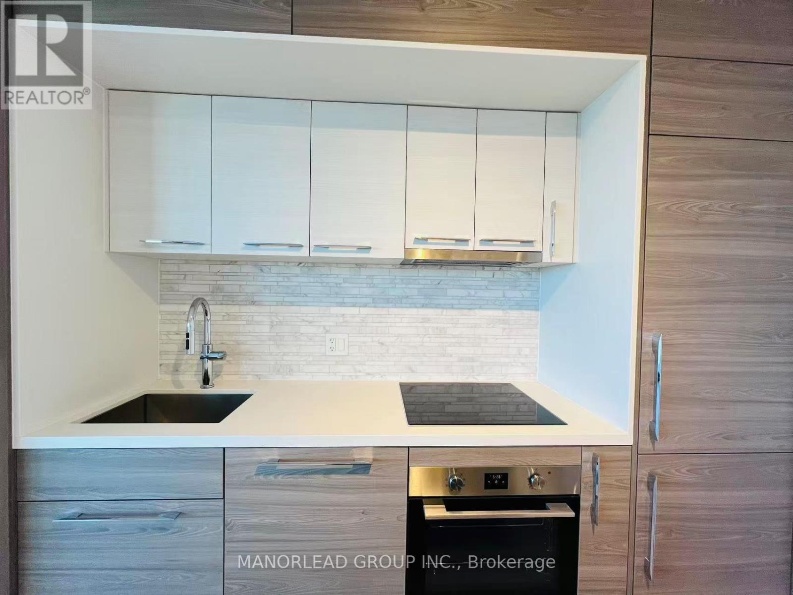A kitchen with white cabinets and a brick backsplash.