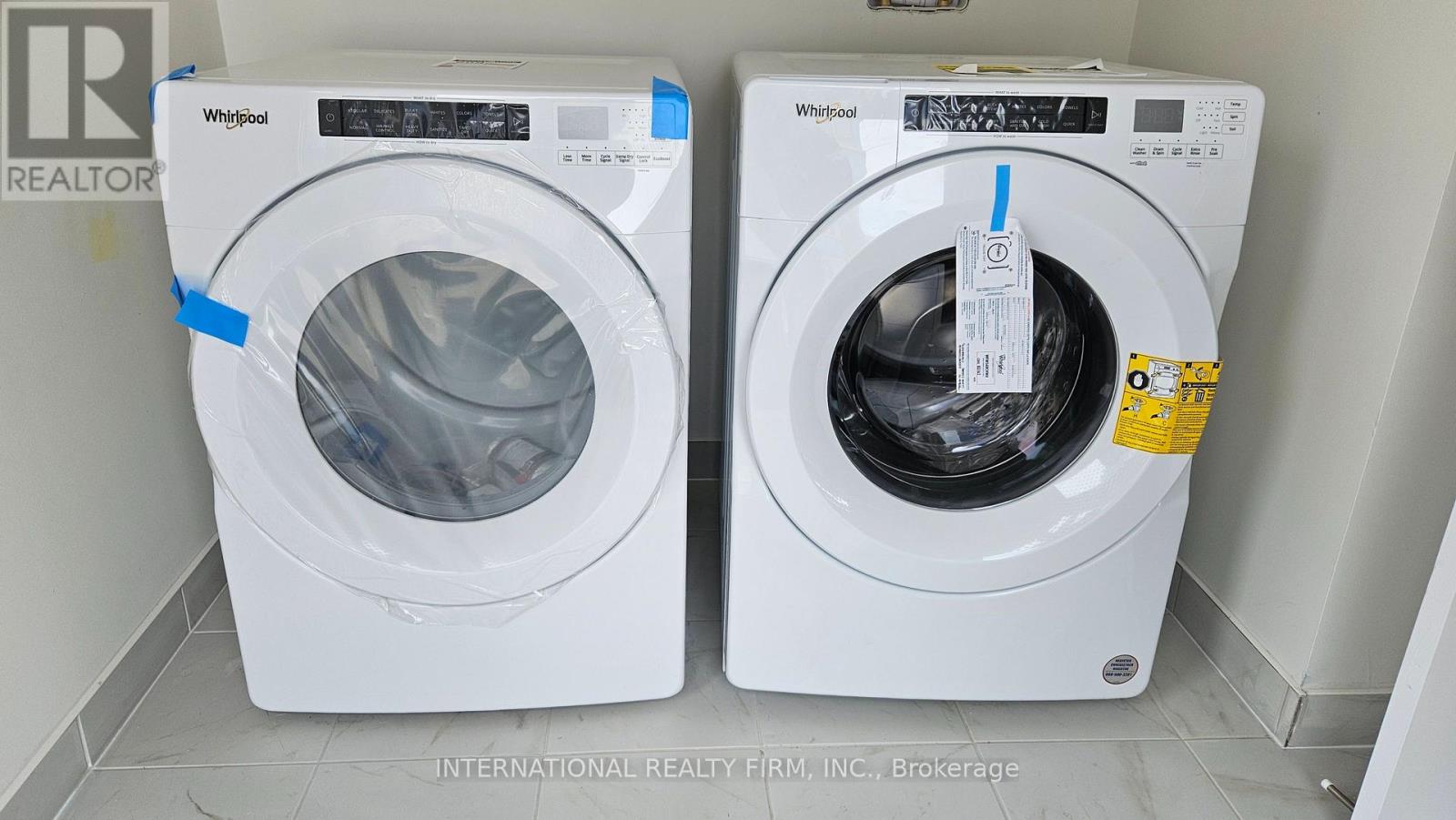 Two Whirlpool washing machines are on display in a brokerage office.