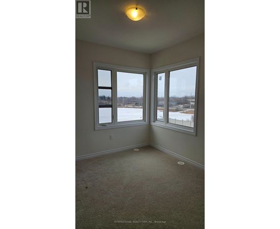 A room with a carpet floor and a window overlooking a snowy landscape.