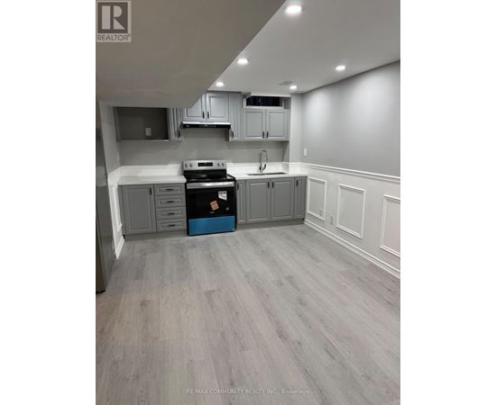 A kitchen with grey cabinets and a black stove top oven.