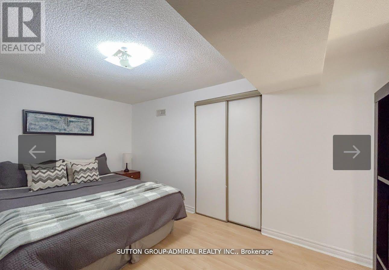 A bedroom with a bed, pillows, and a picture on the wall.