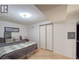 A bedroom with a bed, pillows, and a picture on the wall.