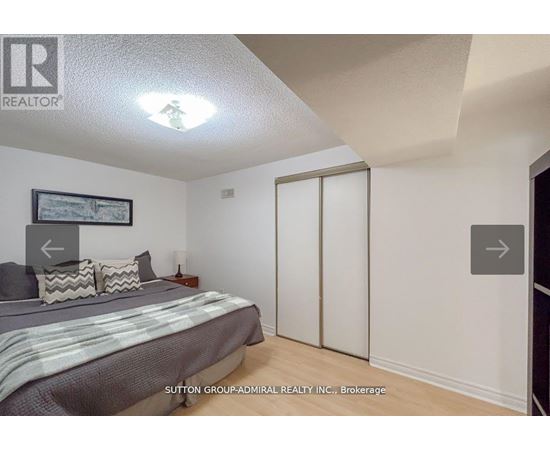 A bedroom with a bed, pillows, and a picture on the wall.
