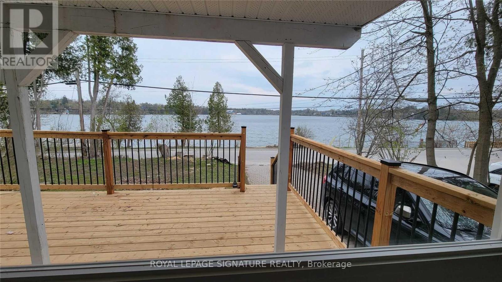 A wooden deck with a metal railing overlooking a body of water.