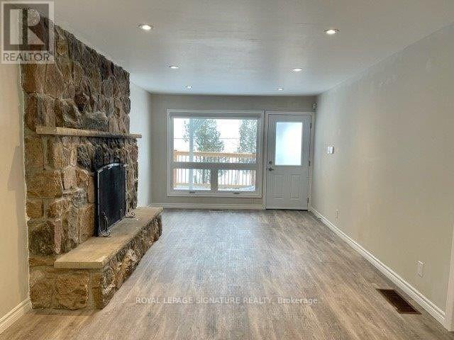 A spacious room with a stone fireplace and sliding glass doors.