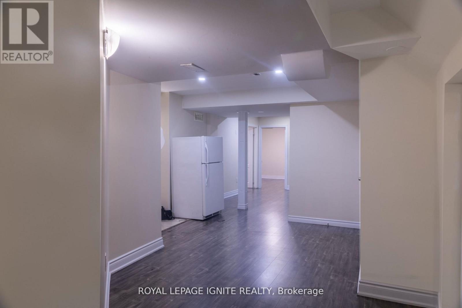 A white room with a fridge and a doorway leading to another room.
